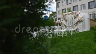 婚礼上一排排椅子。 婚庆花拱装饰.. 用鲜花装饰的婚礼拱门。 室外